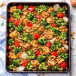 Sheet Pan Cashew Chicken with roasted broccoli, red bell peppers, and golden cashews on a baking sheet.