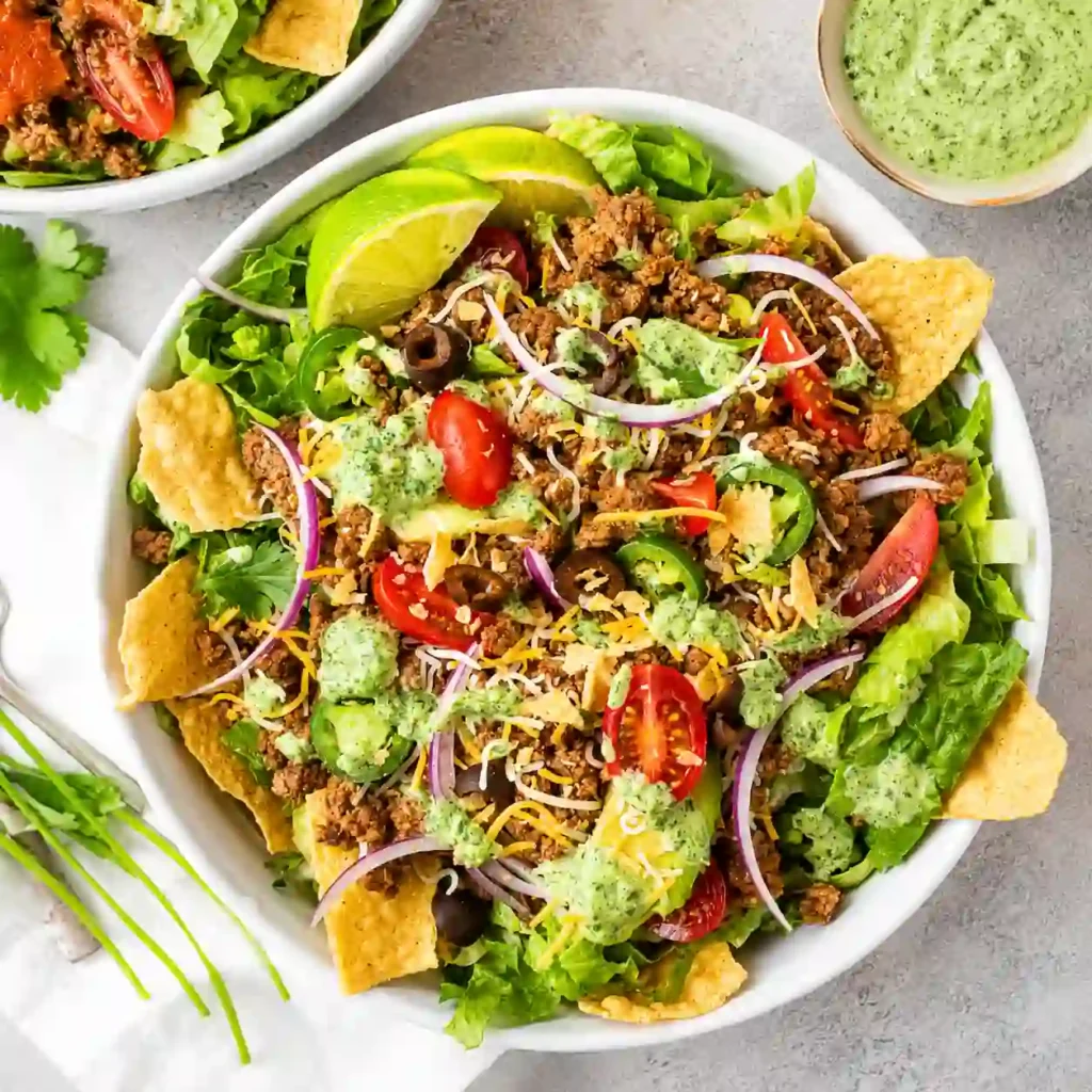 Easy Taco Salad with seasoned beef, lettuce, tomatoes, avocado, cheese, black beans, and tortilla chips.