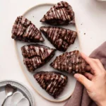 Glazed Triple Chocolate Scones with chocolate drizzle on a marble table.